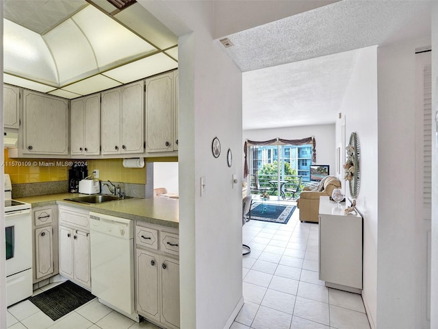 kitchen featuring backsplash, white appliances, a textured ceiling, sink, and light tile floors