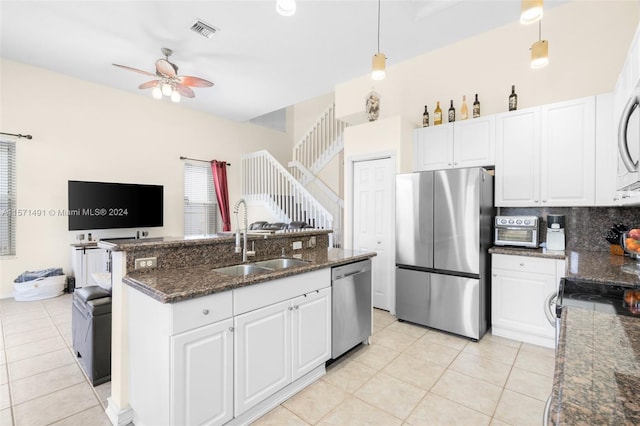 kitchen featuring pendant lighting, white cabinets, appliances with stainless steel finishes, dark stone countertops, and sink