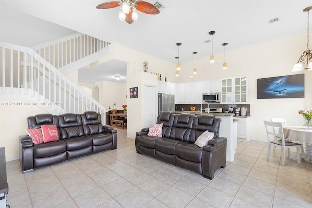 living room featuring a towering ceiling, light tile patterned flooring, and ceiling fan