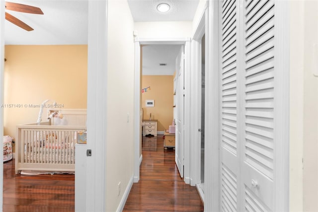 corridor with a textured ceiling and dark hardwood / wood-style floors