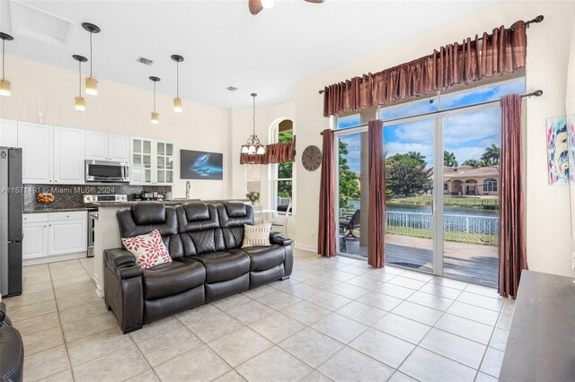 tiled living room with ceiling fan with notable chandelier