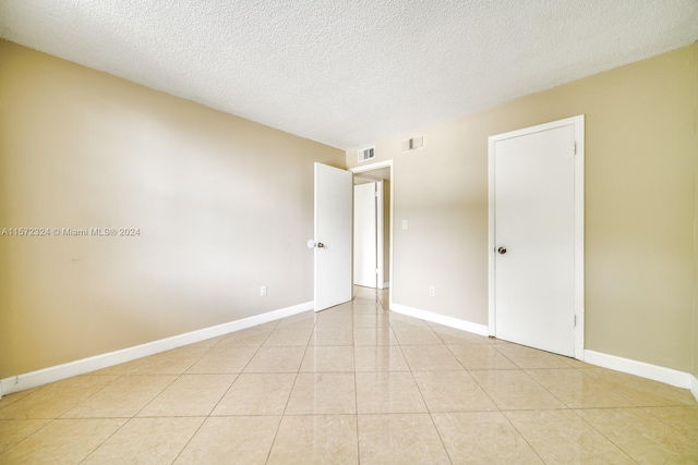 tiled spare room with a textured ceiling