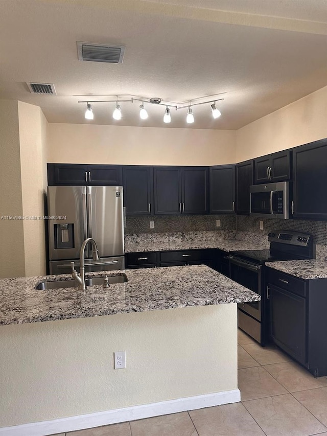 kitchen with appliances with stainless steel finishes, tasteful backsplash, sink, and track lighting