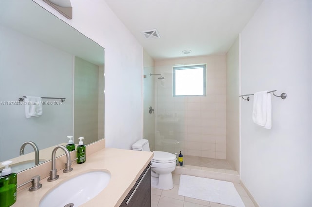 bathroom featuring vanity with extensive cabinet space, tiled shower, toilet, and tile floors