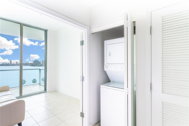 laundry room with stacked washer / dryer and light tile floors