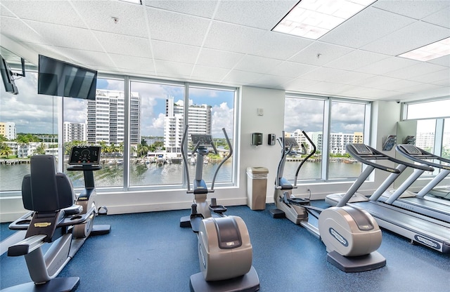 exercise room featuring a paneled ceiling and a water view