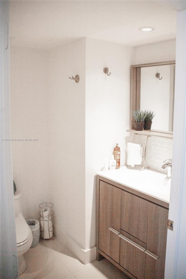 bathroom featuring toilet, decorative backsplash, and vanity