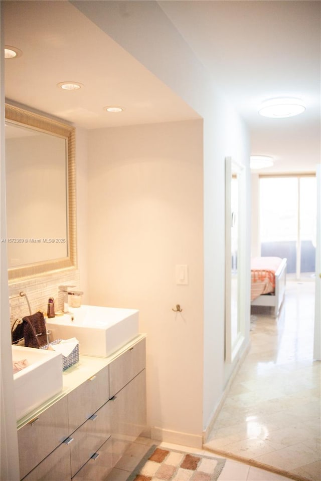 bathroom with double vanity, baseboards, backsplash, and a sink