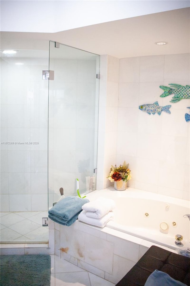 bathroom with a jetted tub, a tile shower, and tile walls