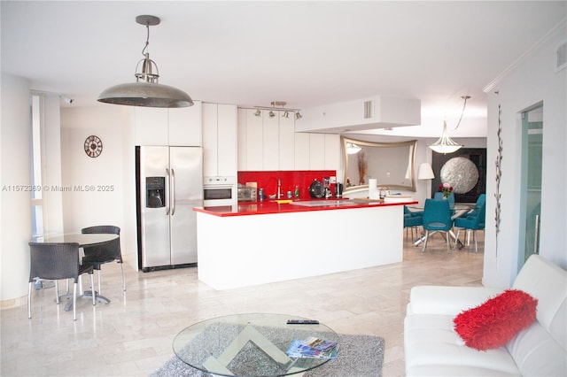 kitchen featuring white oven, stainless steel refrigerator with ice dispenser, white cabinetry, and pendant lighting