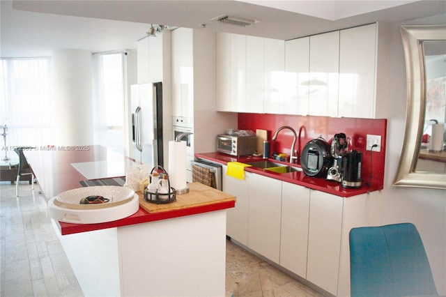 kitchen featuring white cabinets, a sink, visible vents, and stainless steel fridge with ice dispenser