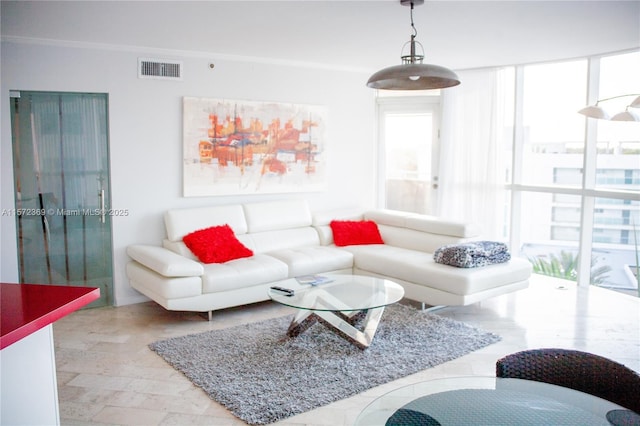 living area featuring plenty of natural light, visible vents, a wall of windows, and ornamental molding