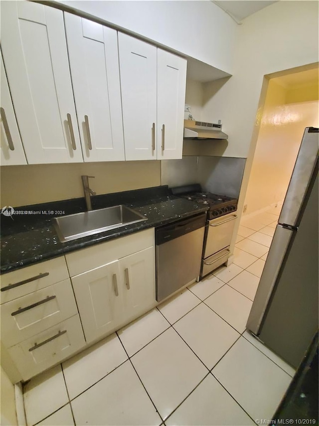 kitchen with appliances with stainless steel finishes, white cabinetry, sink, and light tile flooring