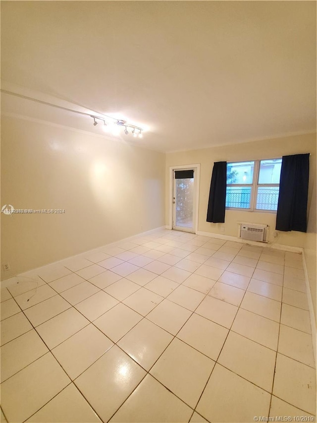 tiled empty room with a wall unit AC and rail lighting