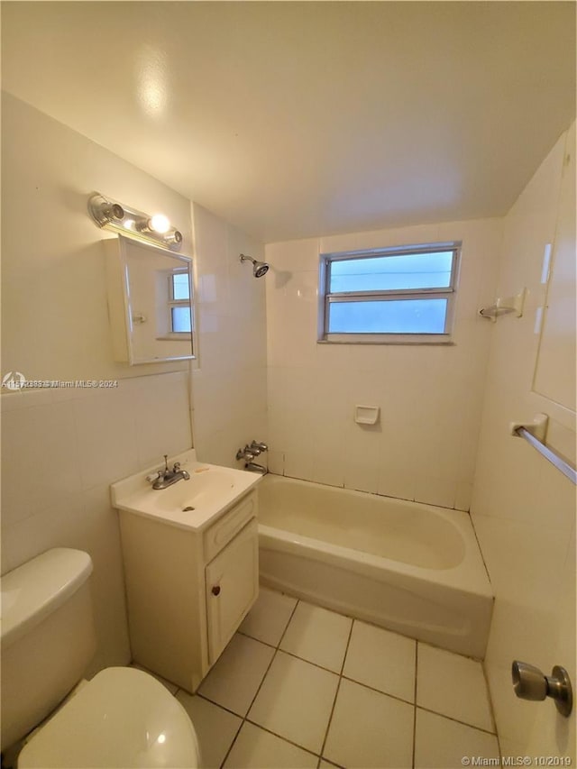 full bathroom with tile flooring, tile walls, tiled shower / bath, toilet, and vanity