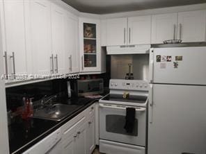 kitchen with white cabinets, sink, white appliances, and wall chimney range hood