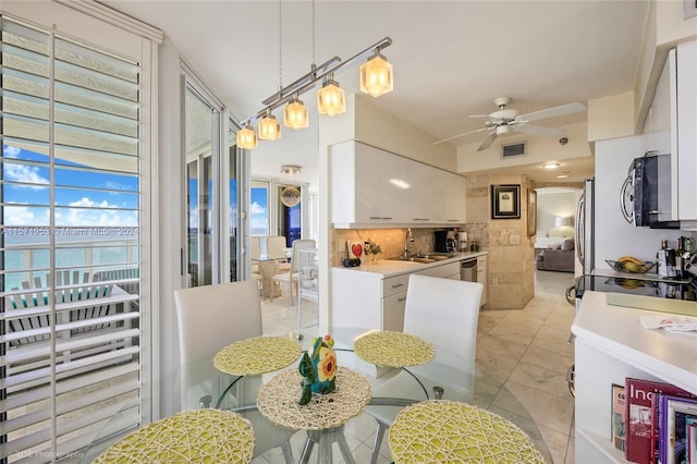 kitchen with light tile flooring, stainless steel appliances, ceiling fan, tasteful backsplash, and white cabinets