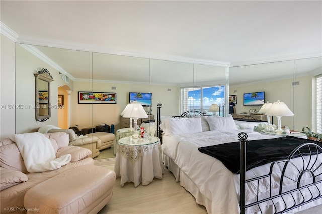 bedroom with ornamental molding and light hardwood / wood-style flooring