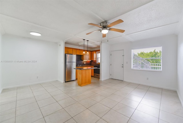 kitchen with kitchen peninsula, backsplash, ceiling fan, light tile flooring, and stainless steel refrigerator