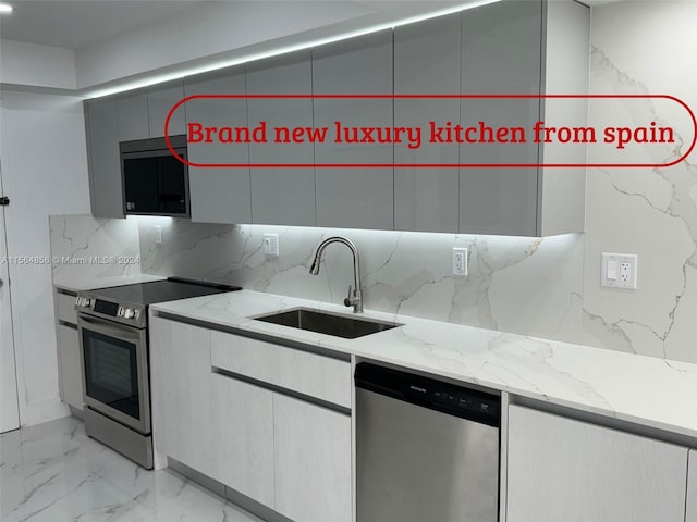 kitchen featuring sink, stainless steel appliances, light stone countertops, and tasteful backsplash