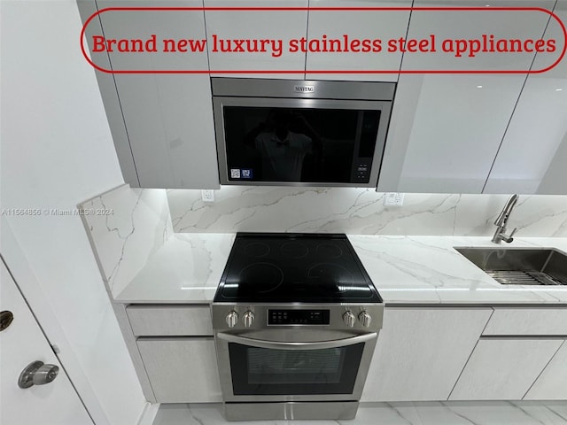 kitchen featuring tile flooring, light stone counters, appliances with stainless steel finishes, sink, and tasteful backsplash