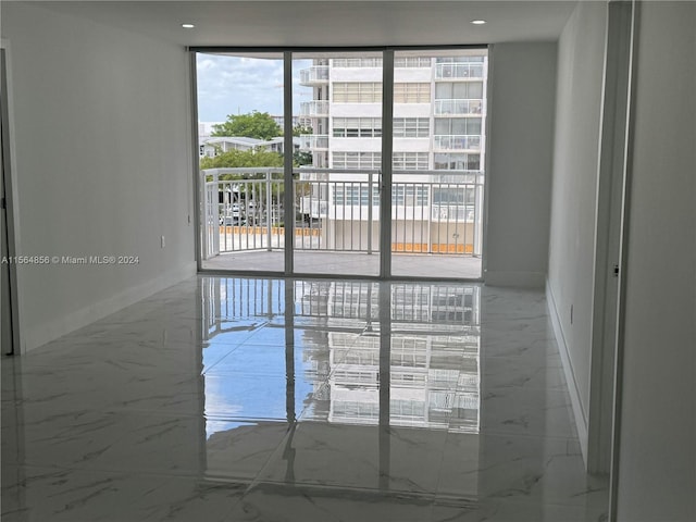 spare room featuring a wealth of natural light, floor to ceiling windows, and light tile floors