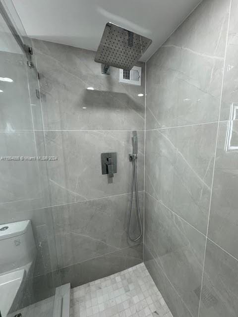 bathroom featuring toilet and a tile shower