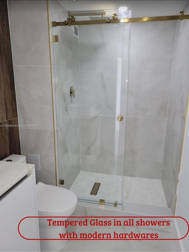 bathroom with a shower with door, vanity, and toilet