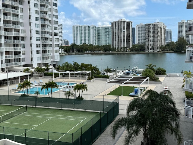 view of tennis court featuring a water view and a community pool