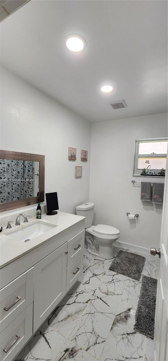 bathroom with tile floors, vanity, and toilet