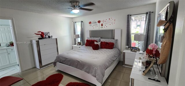 bedroom with a textured ceiling, ceiling fan, ensuite bathroom, and light tile flooring