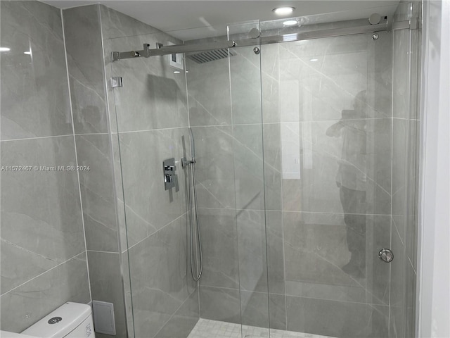 bathroom featuring a shower with door and toilet