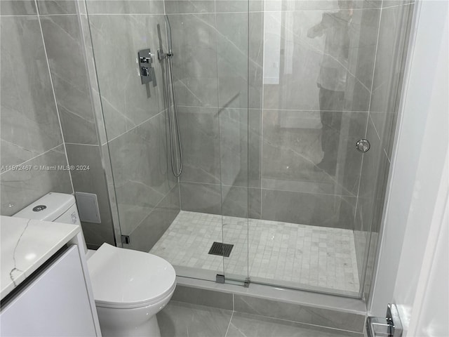 bathroom featuring an enclosed shower, toilet, tile floors, and vanity