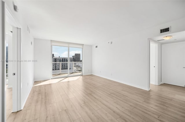 empty room with light wood-type flooring and expansive windows