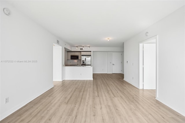 unfurnished living room featuring light hardwood / wood-style floors and sink