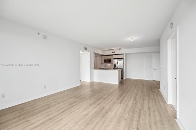 unfurnished living room featuring sink and light hardwood / wood-style flooring