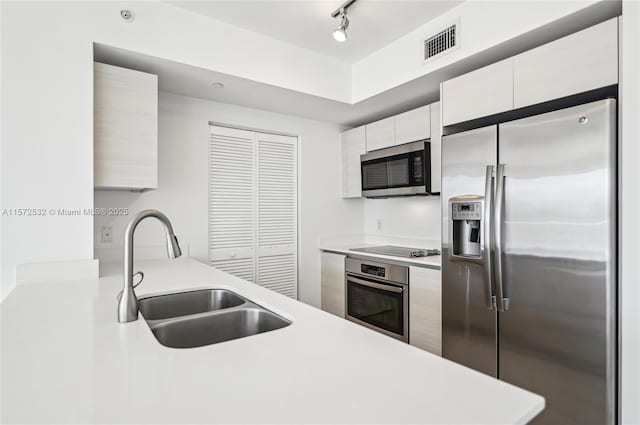 kitchen featuring white cabinets, sink, stainless steel appliances, and track lighting