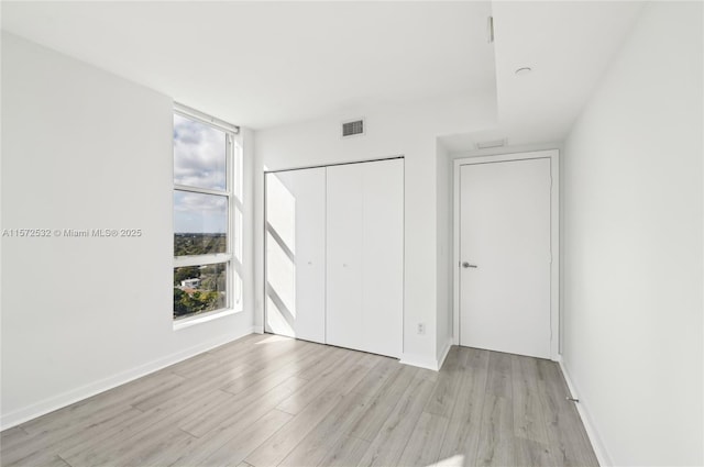 unfurnished bedroom with light hardwood / wood-style flooring and a closet