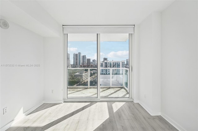 spare room featuring floor to ceiling windows, light hardwood / wood-style flooring, and plenty of natural light