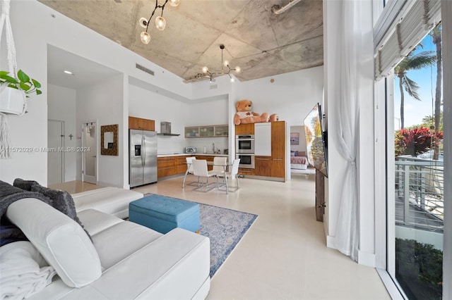 living room featuring a high ceiling, an inviting chandelier, and sink