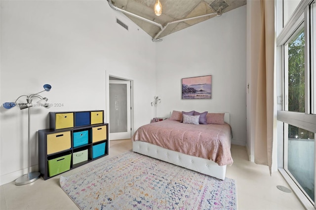 bedroom featuring a towering ceiling and concrete floors