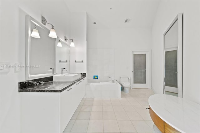 bathroom with tile patterned flooring, vanity, toilet, and a relaxing tiled tub