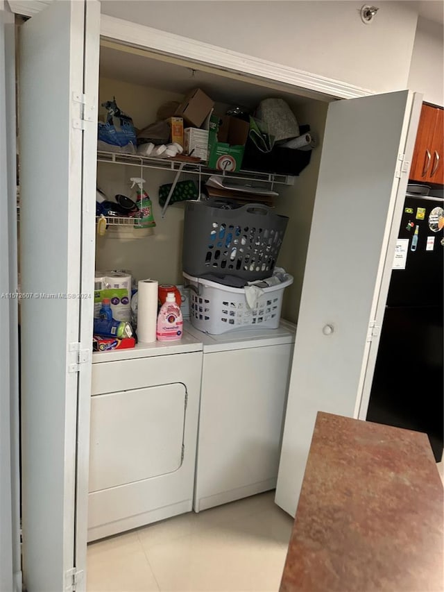 clothes washing area with light tile flooring and washing machine and clothes dryer