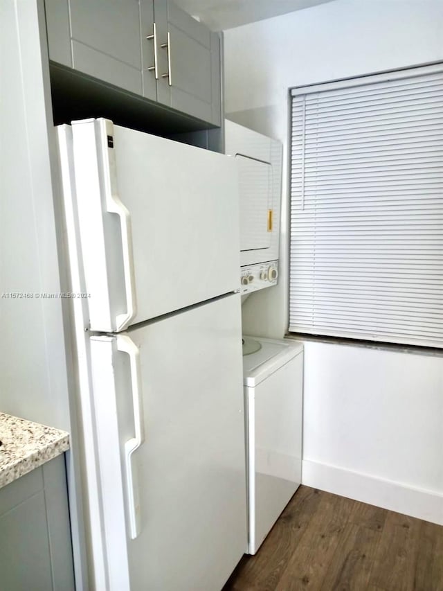 kitchen featuring stacked washer and dryer, white fridge, and dark wood-type flooring