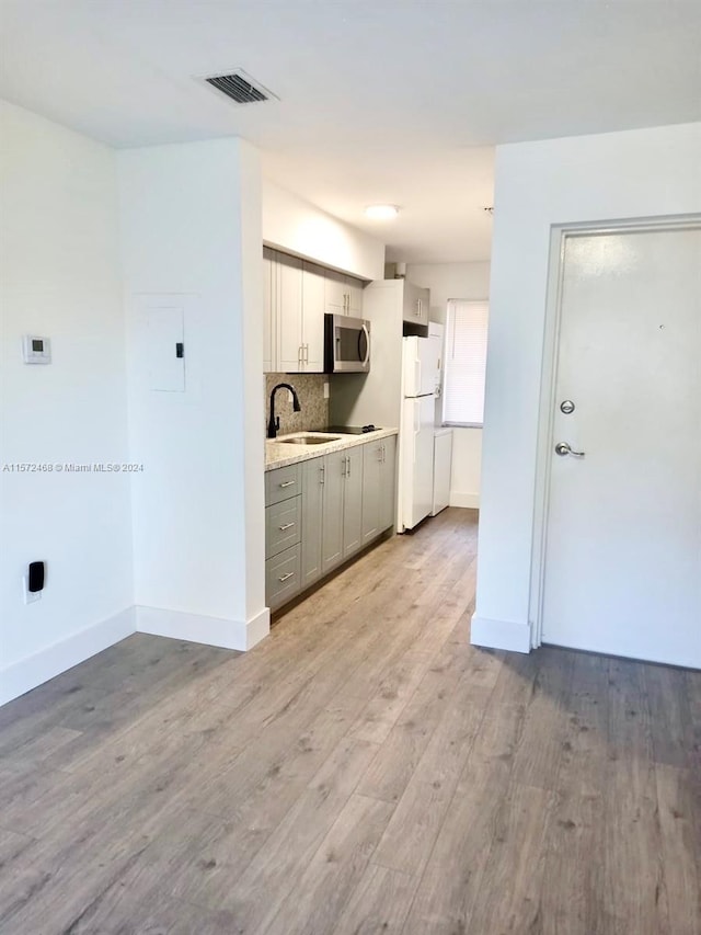 kitchen with white refrigerator, sink, gray cabinetry, and hardwood / wood-style flooring