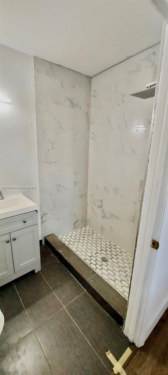 bathroom with tiled shower, tile floors, and vanity