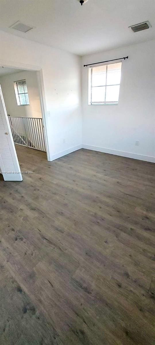 empty room featuring a healthy amount of sunlight and dark hardwood / wood-style floors