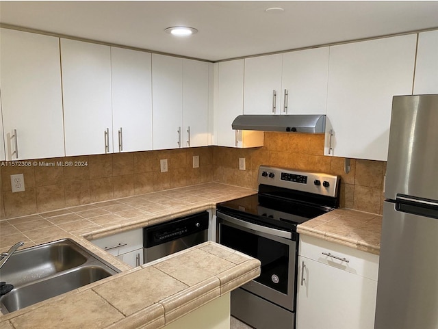 kitchen featuring tasteful backsplash, stainless steel appliances, sink, tile countertops, and white cabinets