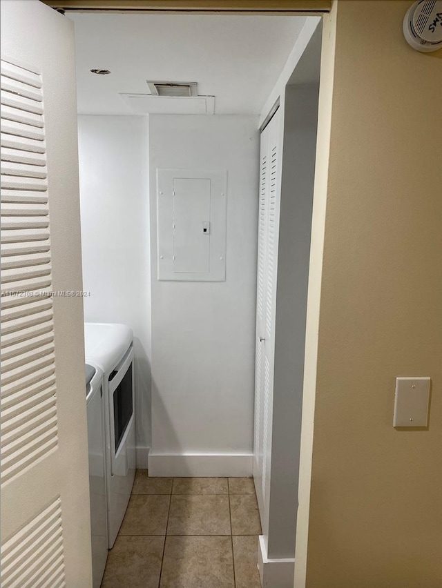 laundry room with light tile patterned floors, washing machine and dryer, and electric panel