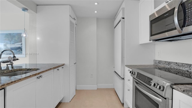 kitchen with decorative light fixtures, appliances with stainless steel finishes, white cabinetry, and stone counters